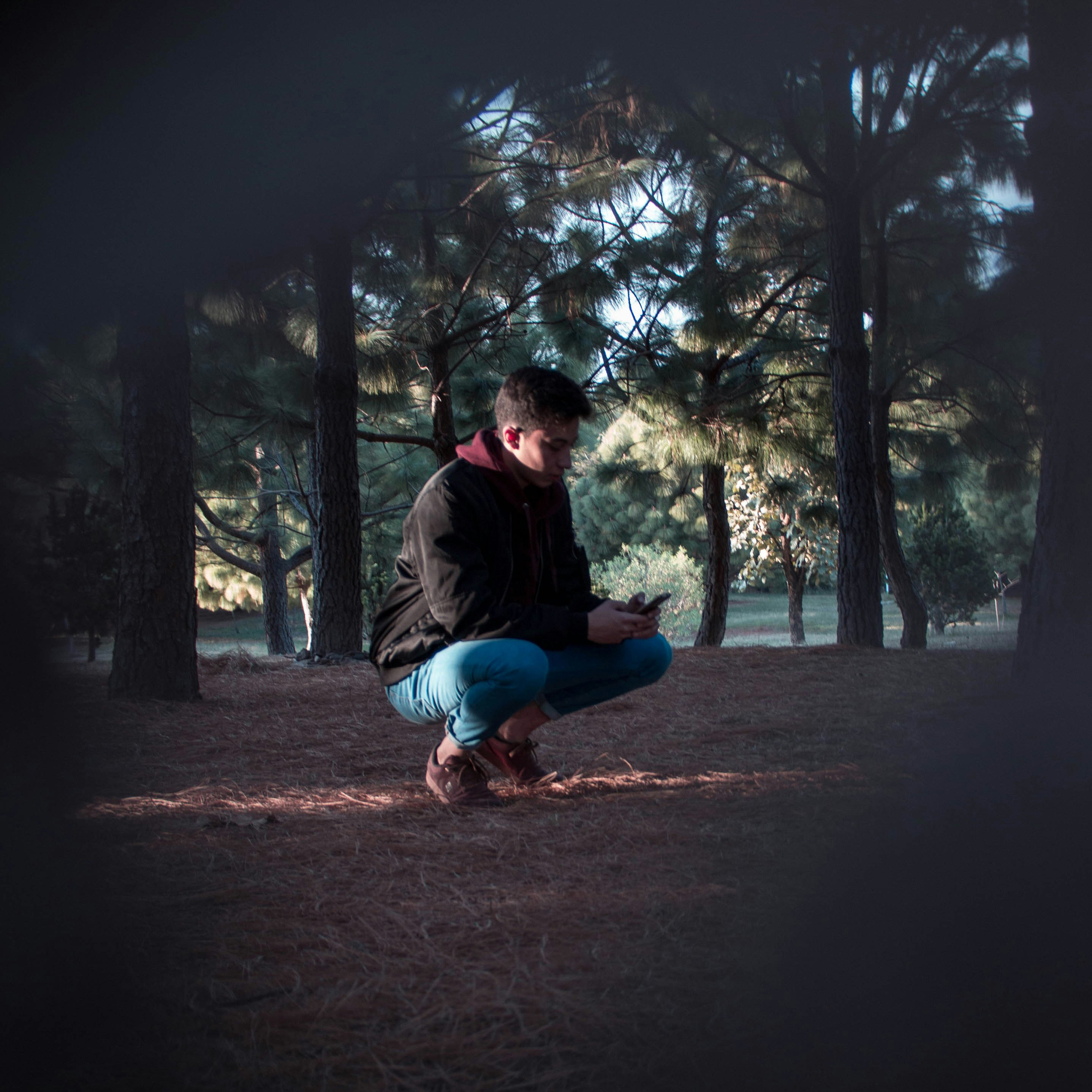 man in forest crouching down taking a picture