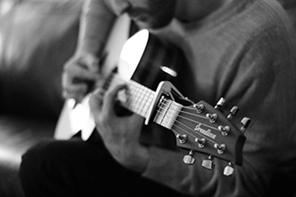 black and white picture of a man playing acoustic guitar
